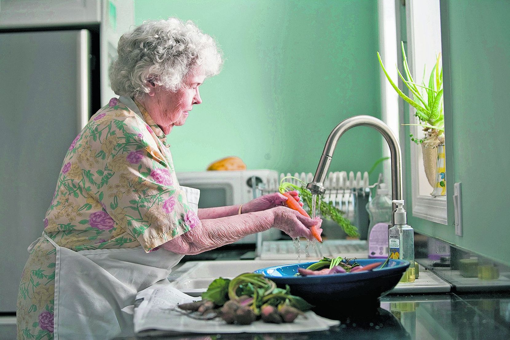 Eine Frau rüstet Gemüse in der Küche.